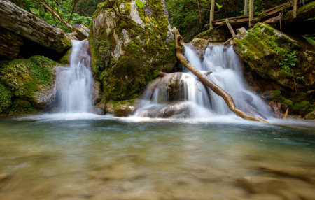 A stream of water flows down a rocky hillside. The water is clear and the rocks are mossyの写真素材