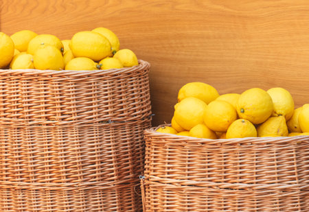 Two baskets of lemons are sitting on a wooden table. The lemons are yellow and appear to be ripeの写真素材