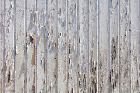 The image is of a wooden fence with peeling paint and a lot of damage. The fence appears to be old and worn, with many areas of it being chipped and broken. Scene is one of decay and neglectの写真素材