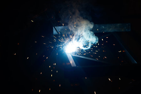 A black and white photo of a piece of metal being welded. The image is of a piece of metal being welded, with sparks flying out of it. Scene is intense and focusedの写真素材