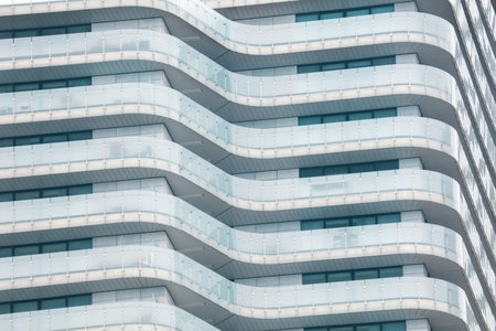 A tall building with a lot of windows and a glass railing. The building is very tall and has a...