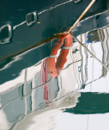 A life preserver is attached to a boat. The water is calm and the boat is in the middle of the waterの写真素材