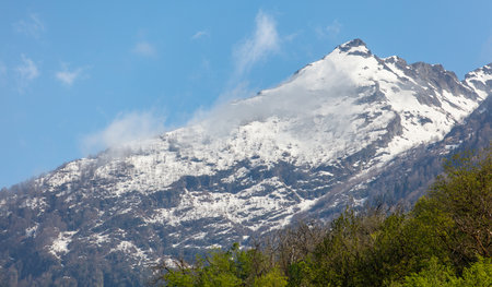 A mountain covered in snow with a clear blue sky in the background. The snow is white and the sky is bright and clearの写真素材