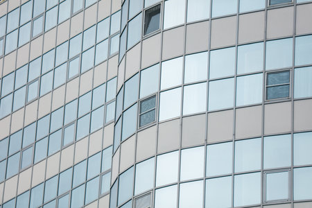 A tall building with many windows and a curved design. The windows are mostly clear, but some are frosted. The building appears to be a modern office buildingの写真素材