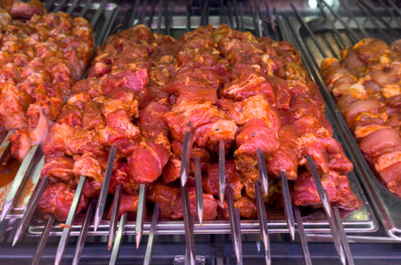 A rack of meat with skewers on it. The meat is marinated and ready to be cookedの写真素材