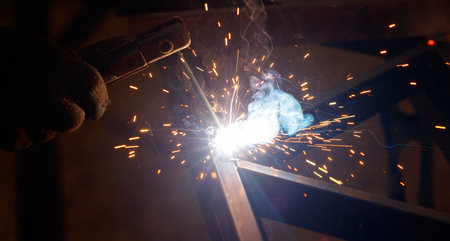 A man is welding a piece of metal with a bright blue flame. Concept of danger and excitement, as the sparks and heat from the welding process can be intense and potentially harmfulの写真素材