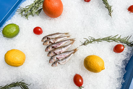 A tray of fish and fruit is on ice. The fish are small and the fruit is colorfulの写真素材