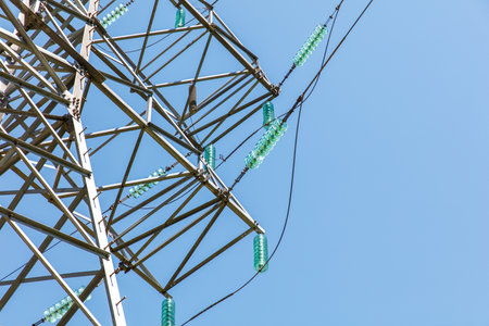 A tall power tower with green and clear bottles on it. The sky is blue and clear. The tower is surrounded by wiresの写真素材