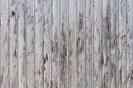 A wooden fence with peeling paint and a lot of damage. The fence appears to be old and worn, with many areas of it being chipped and broken. Scene is one of decay and neglectの写真素材