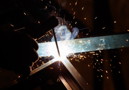 A person is welding a metal piece with a bright light shining on it. Concept of intense focus and...
