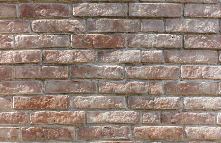 A brick wall with a few bricks missing. The wall is brown and has a rough texture. The missing bricks create a sense of emptiness and abandonmentの写真素材