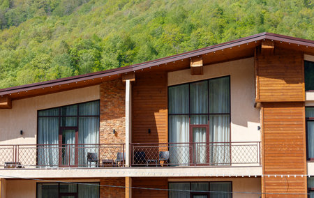 A large house with a balcony and a roof. The house is surrounded by trees and has a rustic feelの写真素材
