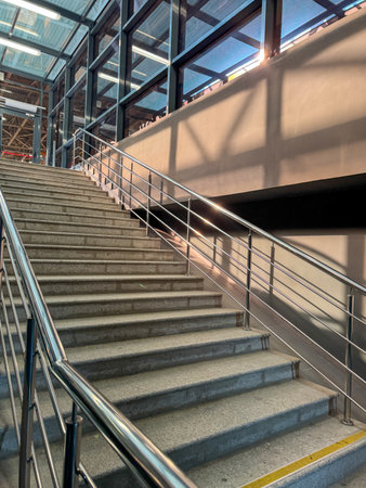 A staircase with a railing and a window above it. The railing is silver and the steps are grayの写真素材