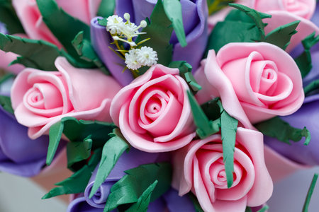 A bouquet of pink and purple roses with white flowers. The roses are made of plastic and arranged in a vase. Scene is cheerful and bright, as the colors of the roses are vibrant and eye-catchingの写真素材