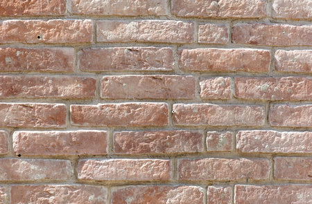 A brick wall with a brown color. The wall is made of bricks and has a rough textureの写真素材