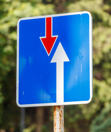 A blue and red sign with an arrow pointing down and another arrow pointing up. The sign is on a poleの写真素材