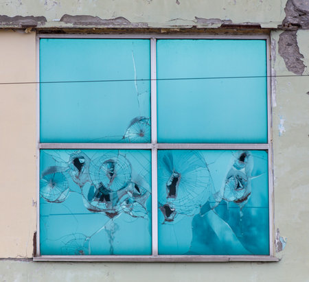 A window with shattered glass and a blue frame. The window is broken and has a blue frameの写真素材