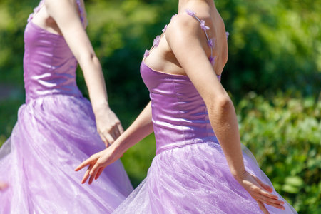 Two women in purple dresses are dancing in a field. Scene is joyful and livelyの写真素材