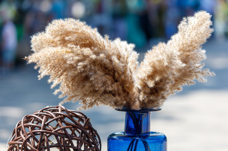 A blue vase with a bunch of brown straws in it. The straws are arranged in a way that looks like a birdの写真素材