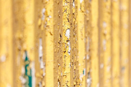 A yellow metal railing with peeling paint. The railing is old and worn, with visible signs of rust and decay. Scene is one of neglect and abandonmentの写真素材