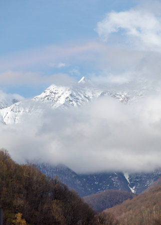 The sky is blue and the mountains are covered in snow. The clouds are white and fluffy, creating a peaceful and serene atmosphereの写真素材
