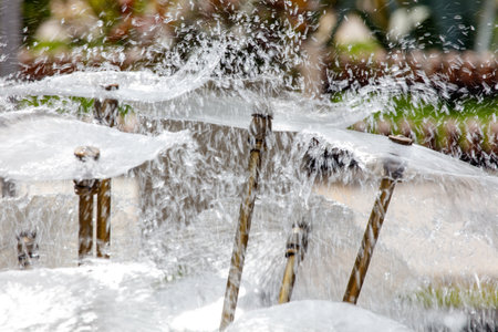 A fountain with water shooting out of it. The water is white and the fountain is surrounded by green grassの写真素材