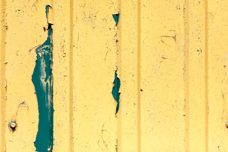 The yellow wall has a green stripe and is covered in peeling paint. The wall is in a state of...