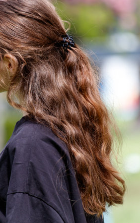 A woman with long brown hair is wearing a black shirt. She has a black hair tie in her hairの写真素材