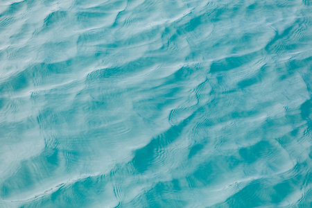 The image is of a body of water with ripples and waves. The water is a deep blue color, and the ripples are visible throughout the entire imageの写真素材