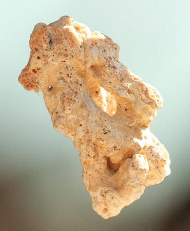 A rock with a hole in it is floating in the air. The rock is white and has a rough texture