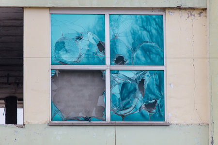 A window with a hole in it and a blue frame. The window is broken and has a lot of holes in it