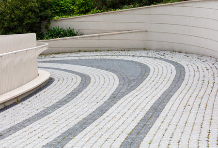 A white and gray stone walkway with a black and gray border. The walkway is curved and has a stone borderの写真素材