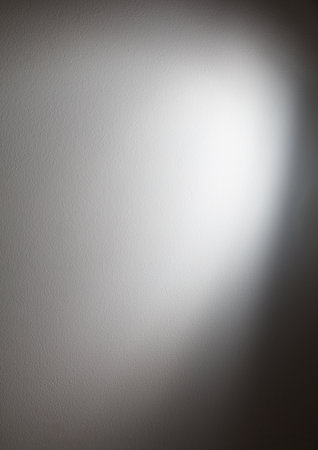A gray wall with a white spot in the middle. The wall is very smooth and has a shiny textureの写真素材
