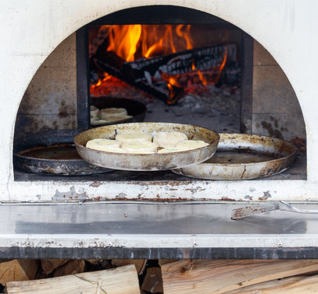 A pizza oven with a pizza inside and a few other pizzas on top of it. The oven is hot and the pizzas...