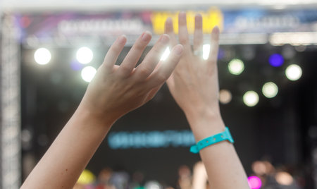 A group of people are clapping their hands together in a concert setting. Scene is energetic and...