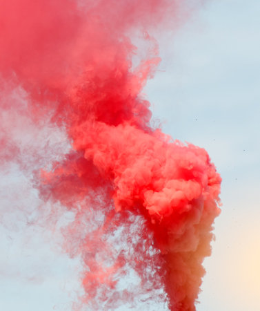 A red cloud of smoke is rising into the sky. The smoke is thick and billowing, creating a sense of...