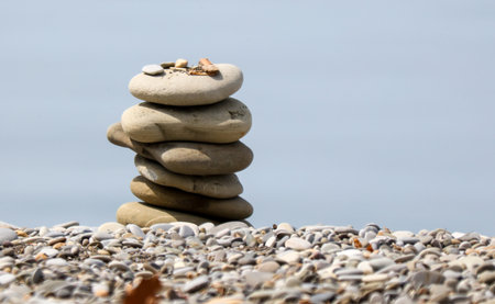 A stack of rocks on a beach with the ocean in the background. The rocks are arranged in a pyramid...