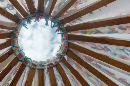 A colorful tent with a hole in the center. The tent is made of wood and has a rainbow of colorsの写真素材