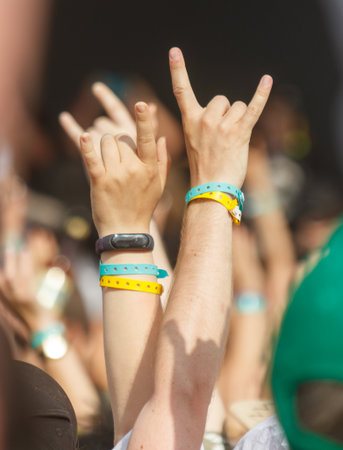 A group of people are holding up their hands and fingers in the air. Scene is energetic and lively,...