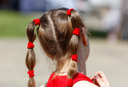 A young girl with red hair has her hair in pigtails. She is wearing a red shirt and a red headbandの写真素材