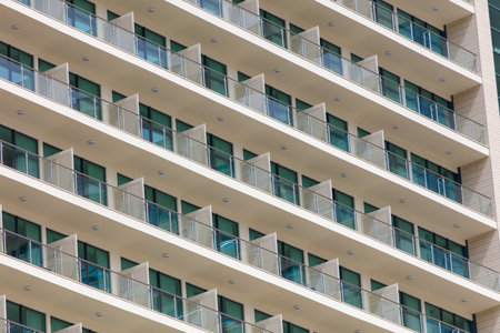 A tall building with many windows and balconies. The windows are open, letting in a lot of lightの写真素材