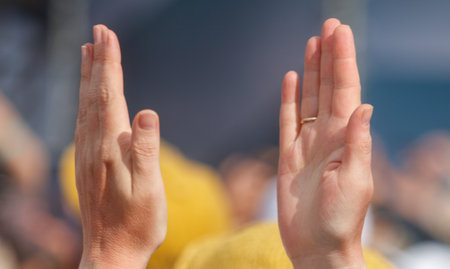 Two hands are raised in the air, one of which is wearing a ring. Concept of celebration or joy, as...