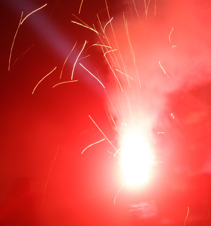 A red background with a white firework in the middle. The firework is surrounded by red sparks