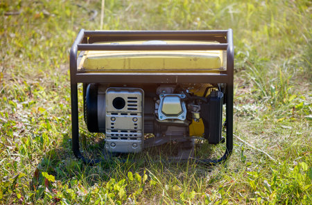 A yellow and black portable generator is sitting on the grass. The grass is lush and green, and the...