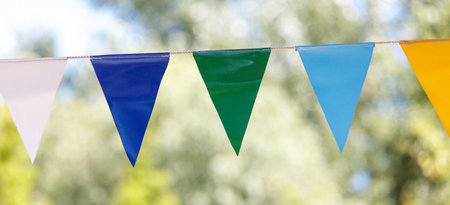 Row of flags with blue, green, and yellow colors. The flags are hanging from a line