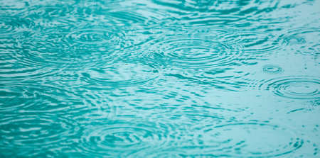 A body of water with raindrops falling on it. The water appears to be calm and still, with the...