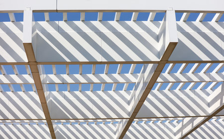 A white structure with a blue sky above it. The structure has a lot of white lines and is open to...