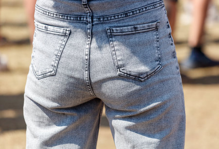 A person wearing jeans with a blue and gray pattern. The jeans are worn by a person who is standing...