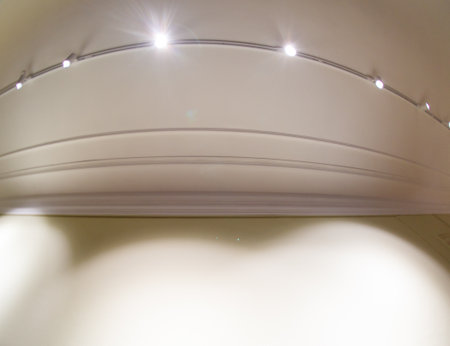A white wall with a light shining on it. The light is on a track