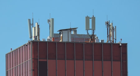 A building with a lot of antennas on top. The building is red and the sky is blue